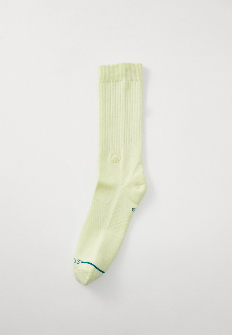Calza gialla chiara fino al ginocchio con texture a coste, caratterizzata da un piccolo logo e una linea blu all'altezza delle dita del piede. Realizzata in tessuto morbido.