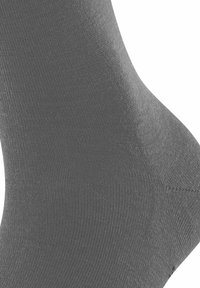 Primo piano di una calza grigia da caviglia che mostra la trama a maglia e i dettagli del tessuto.