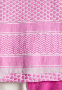 Textil en diferentes tonos de rosa, con patrones geométricos que incluyen pata de gallo y zigzagueos, con una textura suave y un acabado tejido.