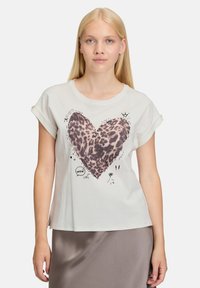 Witte T-shirt met korte mouwen, voorzien van een hartontwerp in luipaardprint, accenten van krabbels en patronen. Zachte stof, relaxte pasvorm.
