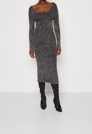 Graues, langärmliges Midikleid mit Rundhalsausschnitt und geripptem Textur, kombiniert mit enganliegenden schwarzen Stiefeln über das Knie mit spitzen Zehen.