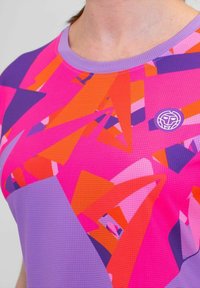 Camisa deportiva morada con un patrón vibrante de formas geométricas en rosa, naranja y morado. Tejido texturizado y transpirable con un acento de logo.