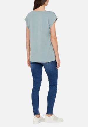 Haut bleu clair à manches courtes avec une coupe décontractée et une texture côtelée, associé à un jean skinny bleu foncé et des baskets blanches.