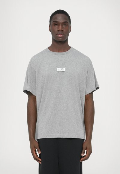 T-shirt gris à manches courtes en coton, doté d'un col rond et d'une étiquette rectangulaire à l'avant. Coupe ample avec un ourlet droit.