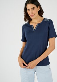 Camiseta de color azul marino con mangas cortas, escote en V y acentos decorativos a rayas en los hombros. Tejido suave con un corte relajado.