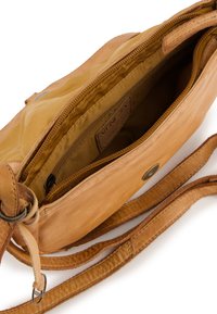 Sacoche en cuir tan avec un intérieur zippé, doublure en tissu et sangle réglable. Présente un rabat avant avec une fermeture pression et un design minimaliste.