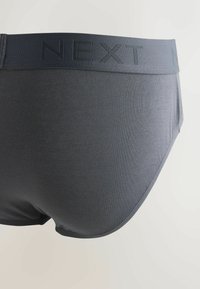 Caleçons pour hommes gris foncé avec une texture lisse et une large ceinture élastique ornée du texte en relief "NEXT".