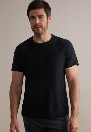 Black crew-neck t-shirt with short sleeves, made of soft fabric. Features a relaxed fit and a slightly curved hem. Simple and versatile design.