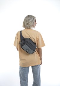 Borsa a tracolla grigia con più scomparti e tracolla regolabile, realizzata in tessuto resistente; presenta una tasca anteriore più piccola e cerniere.