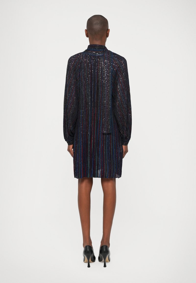 Dark metallic dress with vertical stripes, long puffed sleeves, a high collar, and a slightly flared silhouette, paired with black heeled shoes.