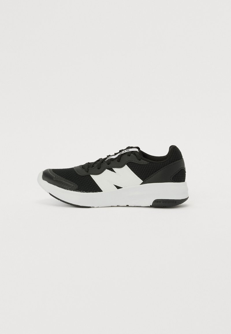 Chaussure de sport noire avec tige en maille, logo blanc, col rembourré et semelle en caoutchouc texturé. Dispose d'un système de laçage et d'un capuchon de protection renforcé.
