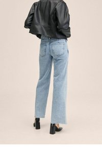 Lysblå højtaljede jeans med løs pasform og frynsede kanter, parret med en cropped sort læderjakke og sorte sko med blokhæl.