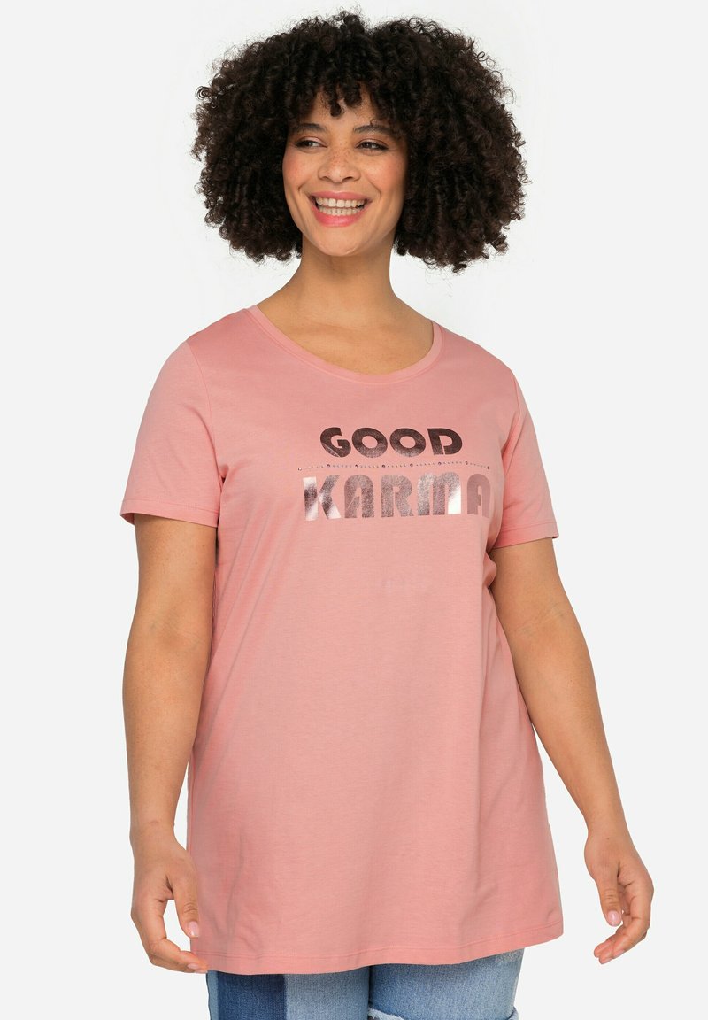 Rosa Kurzarm-T-Shirt mit rundem Halsausschnitt, das den Text "GOOD KARMA" in gemischtem Metallic und fettem Schriftzug auf der Vorderseite präsentiert. Weicher Stoff.