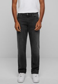 Black denim jeans with a straight fit, five-pocket design, and slight fade. Paired with white sneakers and a plain white t-shirt.