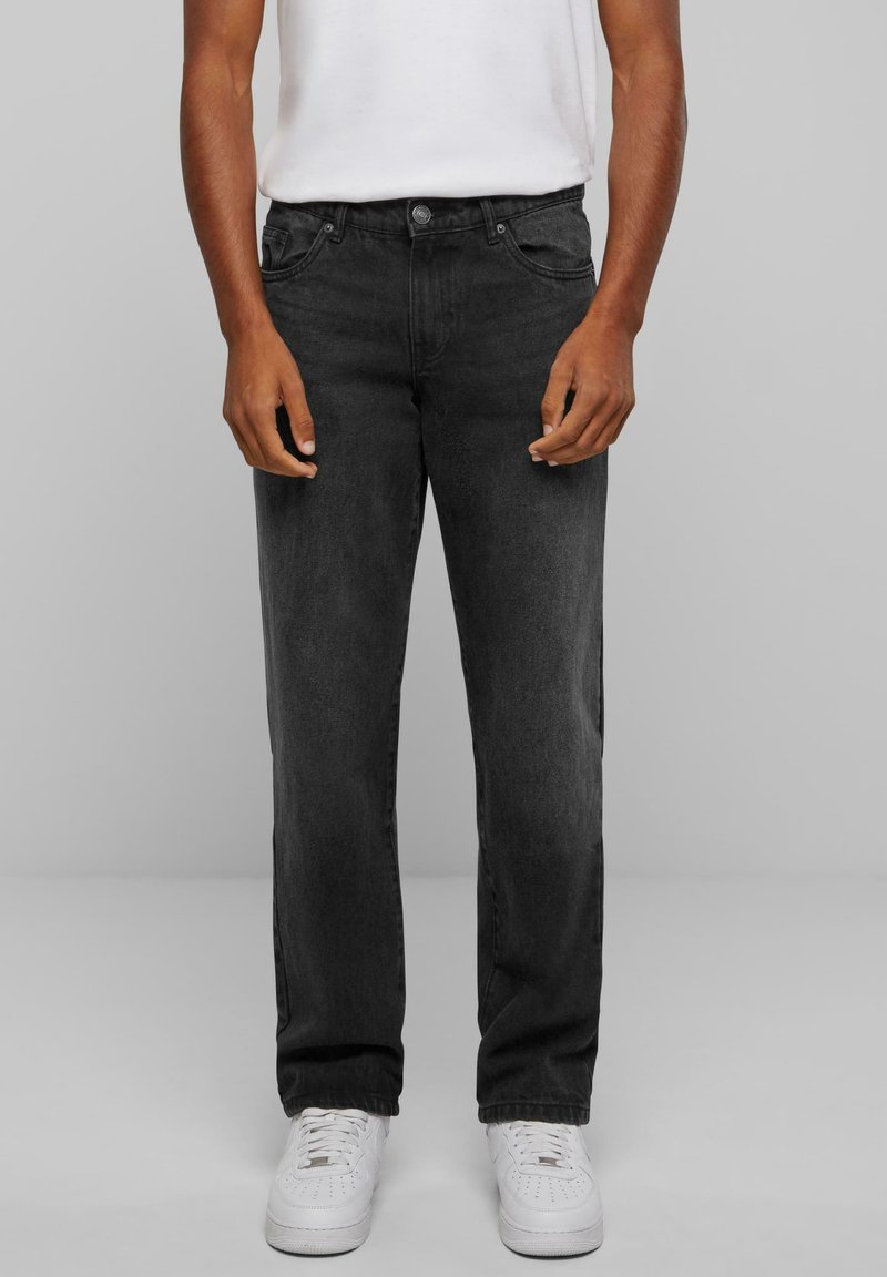 Black denim jeans with a straight fit, five-pocket design, and slight fade. Paired with white sneakers and a plain white t-shirt.