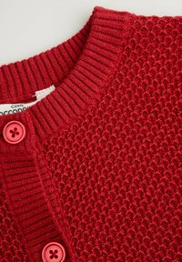 Czerwony sweter na guziki z teksturowanym wzorem dzianiny, prążkowanym kołnierzem i dwoma pasującymi guzikami z przodu do zapięcia.