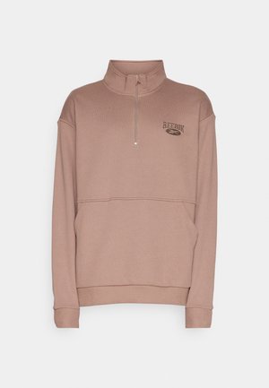 Sweat beige Reebok avec fermeture éclair quart de zip, col montant, manches longues, poche kangourou à l'avant et logo sur la poitrine gauche.