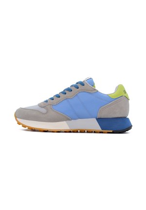 Baskets grises et bleues en matériaux en daim et textile, avec un accent vert au niveau du talon, des lacets bleus et une semelle texturée.