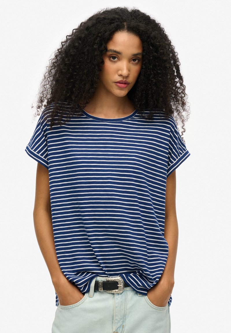 Blauw-wit gestreept t-shirt met korte mouwen, ronde halslijn en een relaxte pasvorm; gecombineerd met lichtblauwe denim broek en een decoratieve riem.