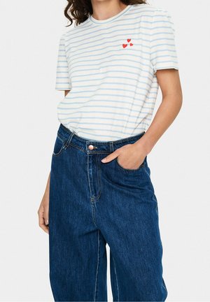 Koszulka w paski w kolorze białym i jasnoniebieskim z krótkimi rękawami i czerwonymi akcentami w kształcie serca, zestawiona z ciemnoniebieskimi dżinsami o wysokim stanie.