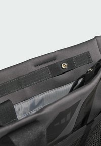 Čierna vnútorná časť tašky na rameno s hladkou sivou podšívkou, zapínaním na patent a popruhom s pevne upevneným bodom prichytenia.