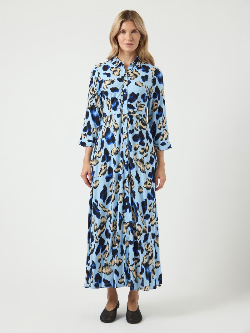 Rochie maxi dintr-o țesătură bleu deschis, cu un model de imprimeu leopard în negru și auriu. Are un design cu guler și detalii cu nasturi, cu mâneci lungi.