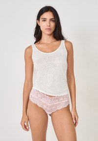 Top en débardeur blanc, fin, avec un col rond, associé à des culottes en dentelle rose ornées de motifs floraux et de bords festonnés.