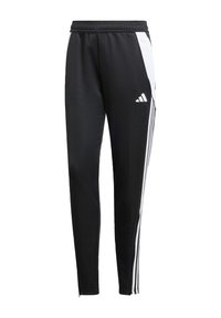 Black athletic pants with a tapered fit, made of smooth fabric. Features white side stripes and an embroidered logo on the left leg.