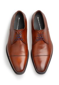 Bruine leren schoenen met een gladde textuur, puntige neus, donkere zool en blauwe veters. Inclusief branding op de binnenzool.