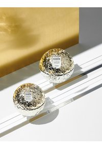 Crema de cuidado de la piel Babor y crema para los ojos en envases de vidrio redondos y texturizados con acentos dorados. Las etiquetas muestran "crema HSR" y "crema para ojos HSR."