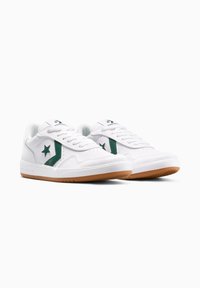Sneakers bianche in pelle con accenti verdi, con logo a stella, lati testurizzati, lacci piatti e suole in gomma color caramello.