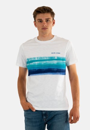 Camiseta blanca con rayas horizontales de pinceladas en turquesa y azul marino. Hecha de material suave, con cuello redondo y mangas cortas.