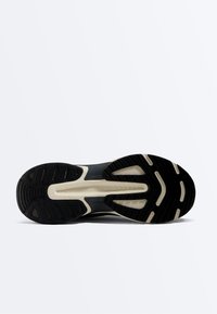 Semelle de chaussure de sport en noir et blanc avec un motif de bande de roulement et la marque "OYSHO" au centre sur un fond blanc.