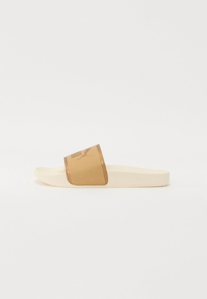 Sandal liuk dengan tali sintetik cokelat muda yang menampilkan logo, dan sol karet berwarna beige muda. Tekstur halus, desain datar, gaya terbuka di bagian depan.