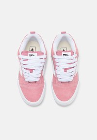 Baskets en daim rose avec lacets blancs, col rembourré et semelles en caoutchouc, présentant un design classique de chaussure de skate et des accents noirs sur les côtés.