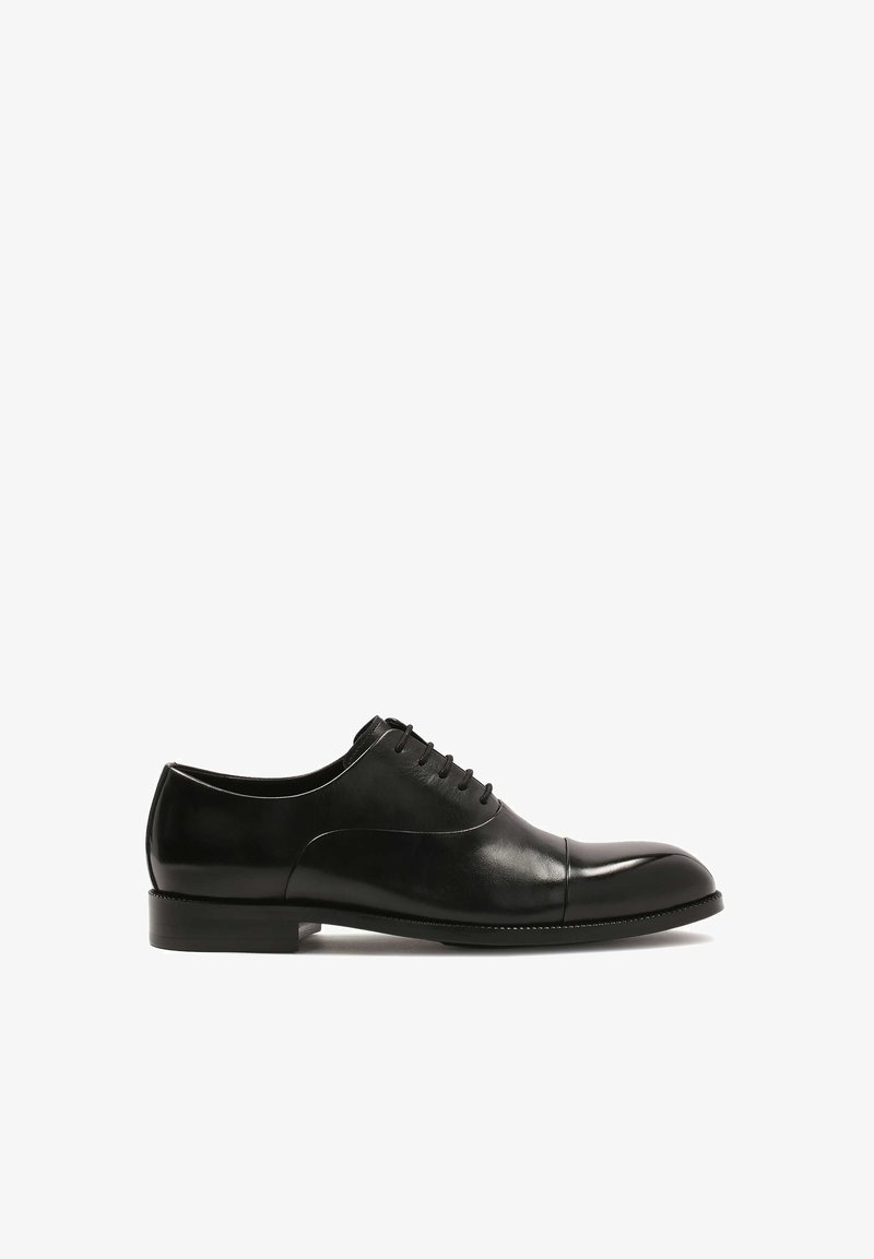 Scarpa da uomo in pelle nera con punta arrotondata, superficie liscia, cuciture minime e chiusura con lacci. Tacco piatto e finitura lucida.