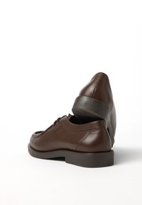 Chaussures en cuir marron avec un bout arrondi, un design à lacets et un petit talon. Texture lisse avec des détails de couture subtils.