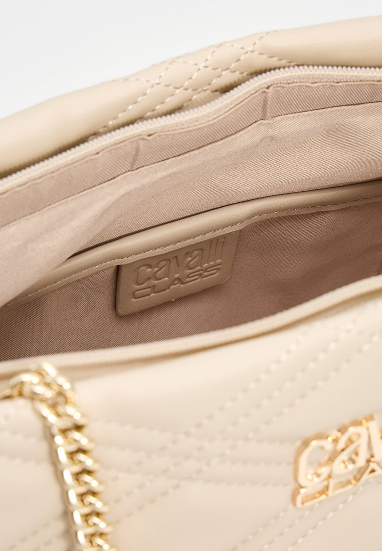 Bolso de mano acolchado beige con un acabado suave, correa de cadena en tono dorado y una etiqueta interior con "Cavalli Class" grabada.