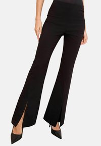Čierne rozšírené nohavice so bočnými rozparkami, vyrobené z hladkej látky. Vysoký pás a priliehavý strih zvýrazňujú nohy. V kombinácii s čiernymi podpätkami.