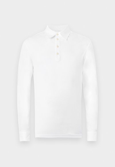 Λευκό πόλο με μακριά μανίκια, κλασικό γιακά και τέσσερα μπεζ κουμπιά κατά μήκος της εμπρόσθιας πατιλέτας.