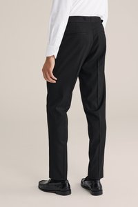 Schwarze Anzughose mit taillierter Passform, glatter Textur, mit Gesäßtaschen und flachem Bund, kombiniert mit polierten schwarzen Slippern.