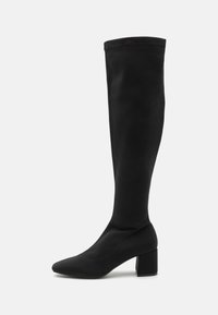 Bota negra hasta la rodilla hecha de material suave, con puntera afilada y un tacón grueso. Diseño sin costuras con acentos mínimos.