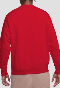 Red sweatshirt featuring a crew neckline, long sleeves, and ribbed cuffs and hem. Smooth texture with no visible patterns or accents.