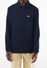 Námořnická polo košile s dlouhým rukávem vyrobená z texturované tkaniny, s tříknoflíkovým zapínáním a zeleným vyšitým logem krokodýla na hrudi.