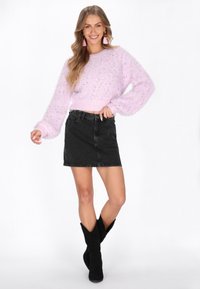 Jasnoróżowy, puszysty sweter z długimi, obszernego rękawami i kolorowymi drobinkami, zestawiony z czarną, dżinsową mini spódniczką i czarnymi, zamszowymi kozakiem do kolan.