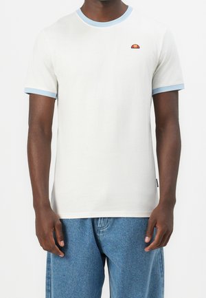 Homme portant un t-shirt blanc à manches courtes avec une bordure bleu clair et un petit logo coloré sur la poitrine, associé à un jean bleu.