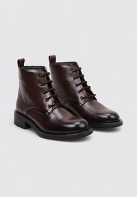 Brown leather ankle boots with a smooth finish, round toe, six eyelet lace-up design, and a low block heel. Flat rubber sole.