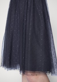 Gonna in tulle blu navy con una sovrapposizione testurizzata decorata con piccoli motivi simili a stelle, design a strati e orlo trasparente.
