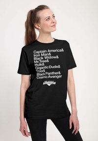 Zwarte katoenen t-shirt met witte tekst waarop superheldennamen staan vermeld, met het logo "NEW JERSEY AVENGERCON" onderaan. Korte mouwen, ronde hals.