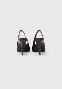 Mustat korkeakorkoiset slingback-kengät, joissa on sileä pinta, terävä kärki ja hoikka stilettokorko, esittelevät minimalistista muotoilua.
